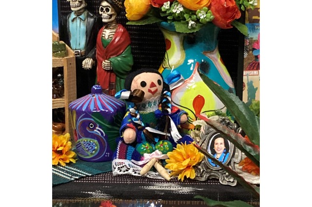 a colorful Mexican ragdoll sits in the Esparza's altar